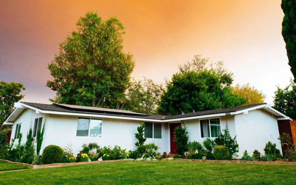 Single-story ranch-style home with solar panels and a landscaped front yard at sunset